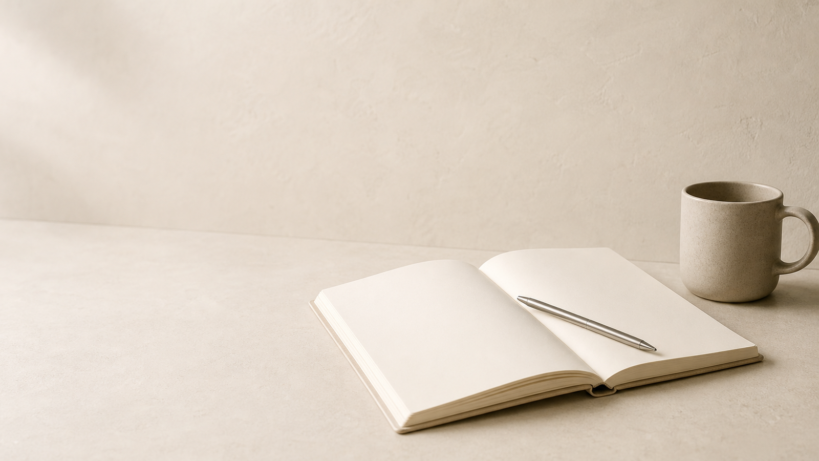 Warm editorial still life with a notebook, pen, and ceramic cup